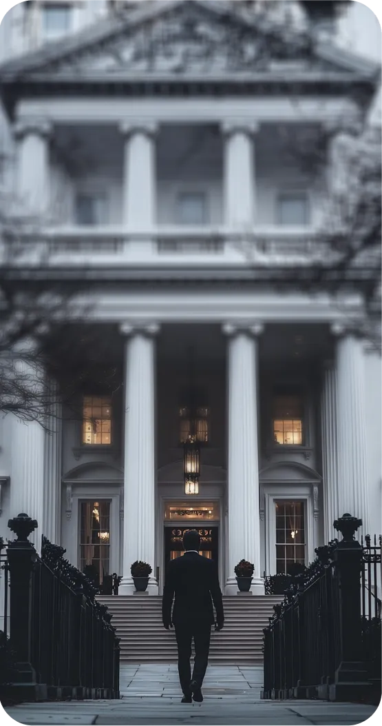 A man in a suit walking up the stairs towards an impressive classical building with columns